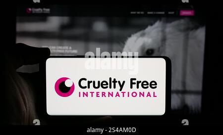 In dieser Abbildung hält eine Person ein Mobiltelefon mit dem Logo der Organisation Grausamkeit Free International auf dem Bildschirm vor der Webseite. Stockfoto