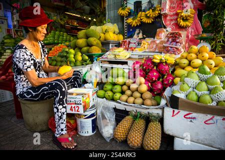 Ho Chi Minh City, Vietnam - January 23, 2018: Vietnamese woman selling an assortment of tropical fruit at a market stall in Ben Thanh Market located i Stock Photo