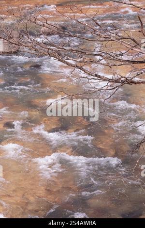 Frühlingsschmelzwasser, das in Flussstromschnellen fließt, brauner Hintergrund Stockfoto