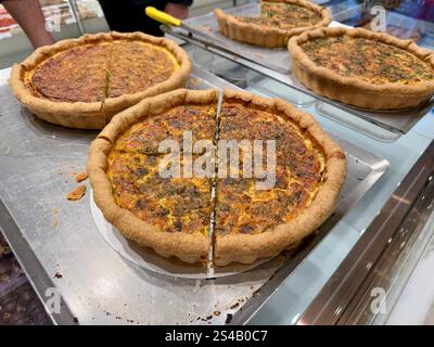 Leckere Spinat-Quiche mit Tomaten und Käse in der Bäckerei zum Verkauf Stockfoto