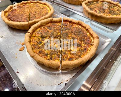 Leckere Spinat-Quiche mit Tomaten und Käse in der Bäckerei zum Verkauf Stockfoto