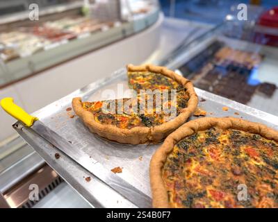 Leckere Spinat-Quiche mit Tomaten und Käse in der Bäckerei zum Verkauf Stockfoto