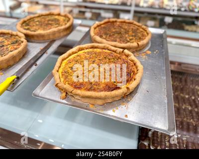 Leckere Spinat-Quiche mit Tomaten und Käse in der Bäckerei zum Verkauf Stockfoto