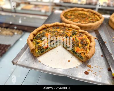 Leckere Spinat-Quiche mit Tomaten und Käse in der Bäckerei zum Verkauf Stockfoto