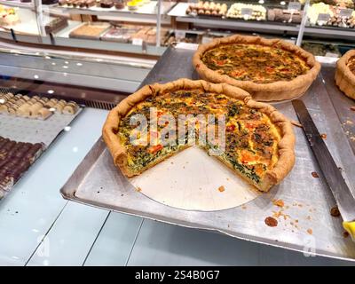 Leckere Spinat-Quiche mit Tomaten und Käse in der Bäckerei zum Verkauf Stockfoto