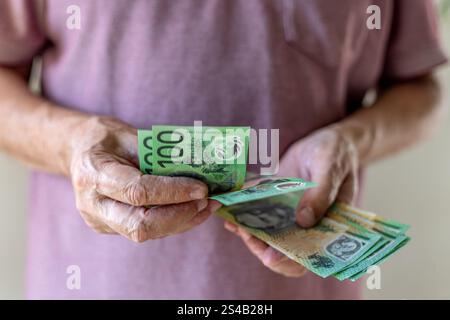 Frontale Nahaufnahme eines Mannes, der 100 australische Dollar-Banknoten zählt. Bargeld-in-Hand-Konzept – Löhne, Zahlungen, Dividenden, Investitionen, Darlehen oder Gewinne. Stockfoto