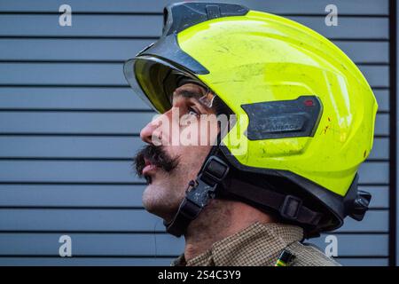 London, Großbritannien. Januar 2025. Ein Feuerwehrmann mit einem kräftigen Schnurrbart beobachtet den Fortschritt - das eisige Wetter lässt eine kleine Menge Mauerwerk von der Spitze eines der vierstöckigen Gebäude auf die Straße fallen. Zahlreiche Polizeibeamte und zwei Feuerwehrfahrzeuge nahmen an dem Unfall im Zentrum von Hampstead Teil. Guy Bell/Alamy Live News Stockfoto