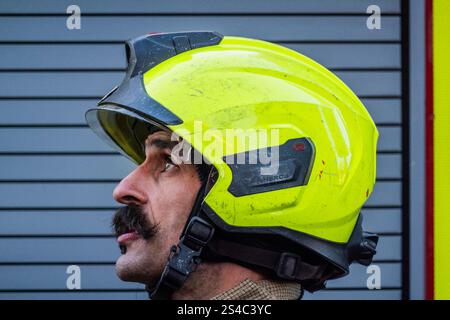 London, Großbritannien. Januar 2025. Ein Feuerwehrmann mit einem kräftigen Schnurrbart beobachtet den Fortschritt - das eisige Wetter lässt eine kleine Menge Mauerwerk von der Spitze eines der vierstöckigen Gebäude auf die Straße fallen. Zahlreiche Polizeibeamte und zwei Feuerwehrfahrzeuge nahmen an dem Unfall im Zentrum von Hampstead Teil. Guy Bell/Alamy Live News Stockfoto