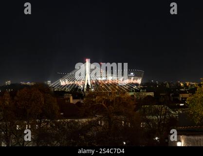 Ein atemberaubender Nachtblick auf ein modernes Stadion, beleuchtet vor dem dunklen Himmel. Die einzigartige Architektur des Stadions und die umliegenden Lichter der Stadt schaffen einen Stockfoto