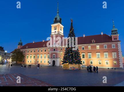 Vor einem historischen königlichen Schloss befindet sich ein wunderschöner Weihnachtsmarkt. Ein großer, geschmückter Weihnachtsbaum steht in der Mitte, umgeben von einer Spitze Stockfoto