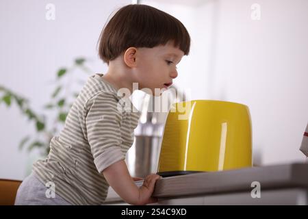 Kleiner Junge, der mit Toaster in der Küche spielt. Gefährliche Situation Stockfoto