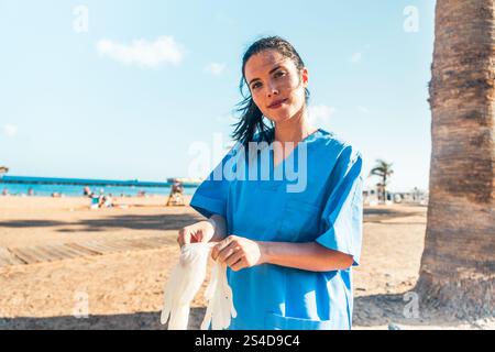 Ein Arzt am Strand zieht zwei Handschuhe an, Gesundheitsfürsorge draußen. Stockfoto
