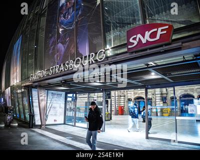 Straßburg, Frankreich - 11. Januar 2025: Der Haupteingang des Gare de Straßburg mit SNCF-Schildern, beleuchteter Glasfassade und zufälligen Fußgängern Stockfoto