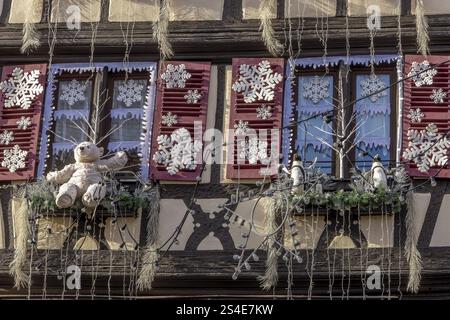 Fachwerkgebäude mit weißen Schneeflocken, einem weißen Teddybären und zwei kleinen Pinguinen am Fenster in der Rue des Marchands, C. Stockfoto