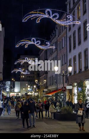 Abend mit einer Straße, die für Weihnachten dekoriert ist, mit festlichen Lichtern in der Luft und Passanten in der Altstadt, Straßburg, Elsass, Departement Bas-RHI Stockfoto