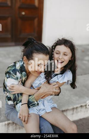 Mutter und Tochter, 10, sitzen zusammen auf Steintreppen Stockfoto