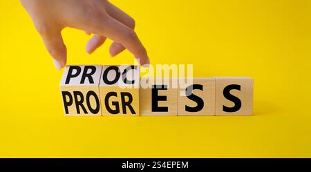 Symbol für Prozess und Fortschritt. Die Hand dreht Holzwürfel und ändert den Wortfortschritt in „Prozess“. Schöner gelber Hintergrund. Business and Process und PROGR Stockfoto