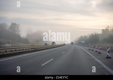 Deutschland, Europa - 20.12.2024: Rückansicht vieler Autos, die bei Nebel auf nassen Autobahnen schnell fahren. Stockfoto