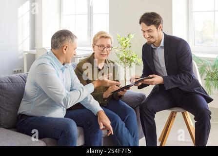 Seniorenpaar im Gespräch mit Finanzagenten über Krankenversicherung im Ruhestand zu Hause. Stockfoto
