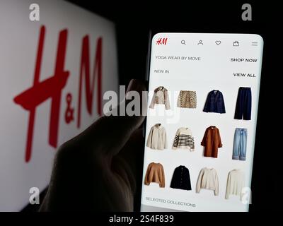 Deutschland. Oktober 2024. In dieser Fotoabbildung hält eine Person ein Handy mit der Webseite des schwedischen Modeunternehmens H and M (H&M) auf dem Bildschirm vor dem Logo. Quelle: SOPA Images Limited/Alamy Live News Stockfoto