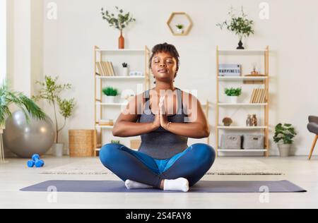 Ruhige Afroamerikanerin, Die Zu Hause In Lotus-Position Meditiert Stockfoto