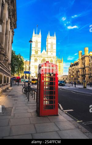 Eine klassische rote Telefonzelle in einer Londoner Straße, perfekt eingerahmt von der historischen Westminster Abbey im Hintergrund Stockfoto