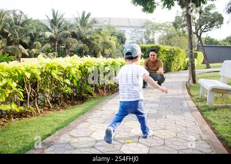 Vater und Sohn spielen zusammen im Park, Baby rennt auf Dad zu Stockfoto