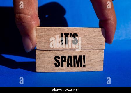 Es ist eine Spam-Nachricht auf Holzblöcken mit blauem Hintergrund. Konzeptionell ist das Spam-Symbol. Kopierbereich. Stockfoto