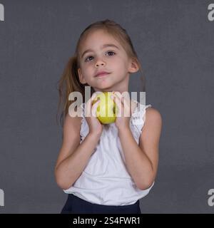 Ein vierjähriges Mädchen hält einen Apfel Stockfoto