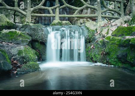 Ruhiger Wasserfall, der über moosige Felsen in einer ruhigen Waldlandschaft stürzt Stockfoto