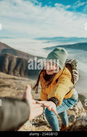 Menschen helfen sich gegenseitig, bei Sonnenaufgang einen Berg hinauf zu wandern. Stockfoto