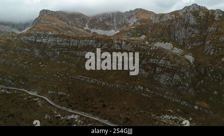 Schmale Autostraße zum Sedlo - Sattelpass, nördlich des Montenegro Durmitor National Park. Draufsicht von der Drohne. Ruhige, bewölkte Herbstlandschaft Stockfoto