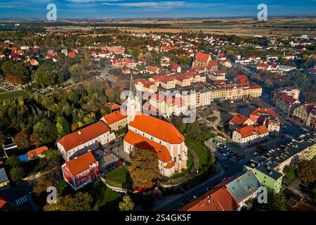 Blick aus der Vogelperspektive auf die europäische Stadt mit farbenfrohen Gebäuden und Kirche bei Sonnenuntergang. Vorstadtlandschaft mit roten Dachhäusern in einer kleinen Stadt, umgeben von üppigen Bäumen Stockfoto