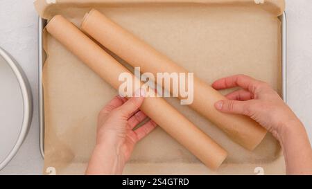 Im Moment des Backprozesses legen die Hände einer Frau gekonnt Pergamentpapier auf eine Backform Stockfoto