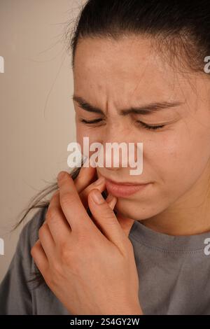 Die Frau fängt ihr Zahnfleisch mit einem schmerzhaften Ausdruck an und fängt das Gefühl von Zahnschmerzen ein. Ihre Körpersprache spiegelt körperliche Unannehmlichkeiten wider. Die Stockfoto