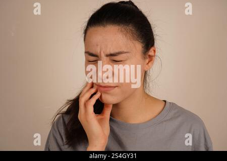 Ihre Körpersprache spiegelt körperliche Unannehmlichkeiten wider. Der Moment ist eine echte Darstellung des persönlichen Unbehagens. Die Frau bindet ihr Kaugummi mit Schmerzen Stockfoto