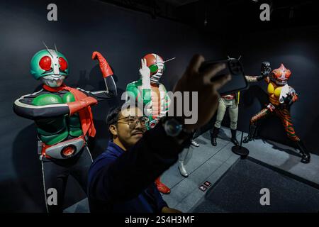 Ein Fan der Kamen-Rider-Serie macht ein Selfie mit der Nachbildung des Kamen-Riders während der 50. Jubiläumsausstellung in Kuala Lumpur, Malaysia, am 12. Januar 2025. Die Ausstellung feiert die legendäre japanische Superheldenreihe, die Fans seit Generationen in ihren Bann zieht. Über 50 lebensgroße Nachbildungen von Kamen Riders und Requisiten aus den Showa-, Heisei- und Reiwa-Zeiten erwecken die Kamen Rider-Charaktere durch Originalkostüme, ikonische Requisiten und reproduzierte Manga-Panels zum Leben. (Foto: Hari Anggara/NurPhoto) Stockfoto