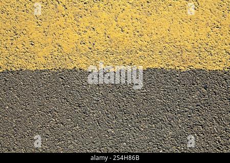 Asphaltoberfläche, Hintergrund. Ein alter Asphalt, bedeckt mit gelber Farbe. Straßenhintergrund mit gelbem Teilstreifen unten. Detaillierte Textur Stockfoto