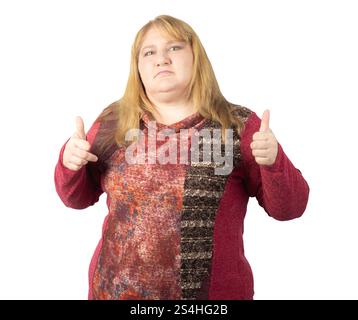 Eine Frau mittleren Alters, die ihre Zustimmung mit einer doppelten Daumen-nach-oben-Geste ausdrückt. Sie trägt einen gemusterten roten Pullover und hat einen ernsthaften Ausdruck. Stockfoto