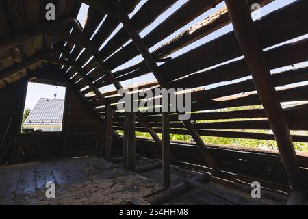 Abstrakter dunkler grunge hölzerner Hintergrund, perspektivischer Blick auf einen verlassenen Dachboden mit gebrochenem Dach und leerem Fenster Stockfoto