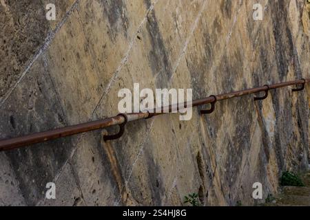 Rostiger Handlauf entlang der Steinmauer mit verwitterter Oberfläche und erdiger Ästhetik Stockfoto
