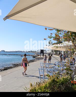 Eine junge Frau läuft am Meer entlang in Richtung Hafen in Paphos Stadt, Zypern. Oktober 2024 Stockfoto