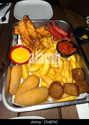 Verschiedene Biersnacks, Chicken Nuggets, Pommes frites, Shrimps Temputa und Chicken Wings in der Pub Bar Stockfoto