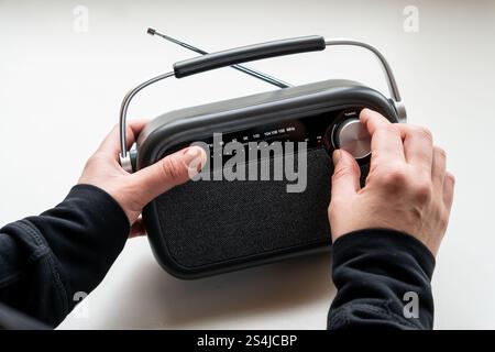 Nahaufnahme von weiblichen Händen, die ein graues Radio im alten Stil hören Stockfoto