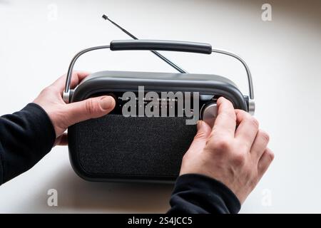 Nahaufnahme von weiblichen Händen, die ein graues Radio im alten Stil hören Stockfoto