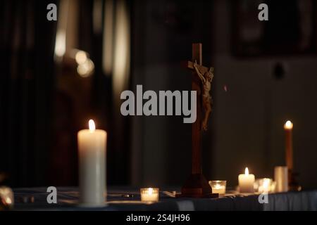Hintergrundaufnahme des hölzernen Kreuzes auf dem Tisch in der Kirche oder Kathedrale mit Kerzen beleuchtet, Kopierraum Stockfoto