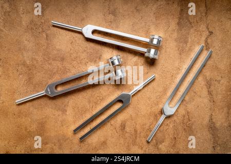 Satz gewichteter und ungewichteter Stimmgabeln aus Metall, die zum Abstimmen von Musikinstrumenten, zur Klangtherapie, zur Chakra-Heilung oder Entspannung verwendet werden. Stockfoto