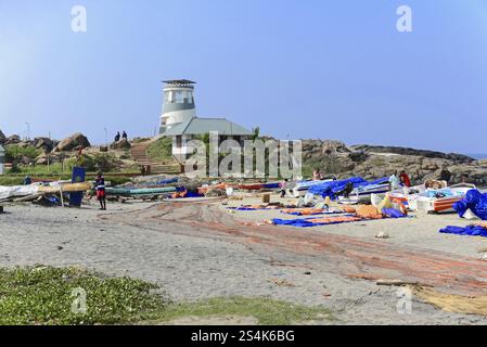 Kovalam Beach, Malabar Coast, Malabar, Kerala, Südindien, Indien, Asien, Eine geschäftige Küste mit Booten und Menschen, ein Leuchtturm im Hintergrund, Koval Stockfoto