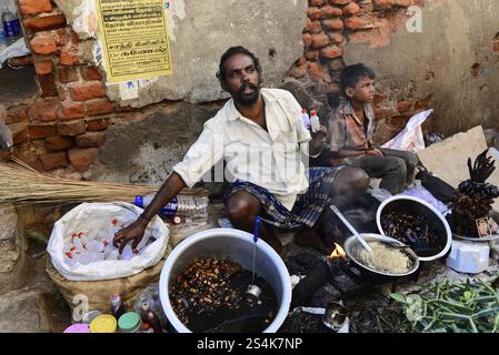 Kanyakumari oder Kanniyakumari, südlichstes Dorf Indiens, Kap Komorin, Tamil Nadu, Südindien, Ein Mann und ein Junge sitzen neben einer Backsteinmauer und Prepa Stockfoto