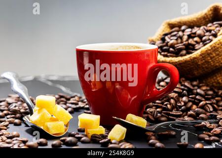 Eine Tasse schwarzer heißer Kaffee serviert mit braunen Zuckerwürfeln und Kaffeebohnen auf einem alten hölzernen Hintergrund. Kopierbereich Stockfoto